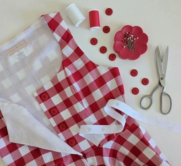 Vestido de xadrez vermelho com botões forrados, linha, alfinetes e tesoura